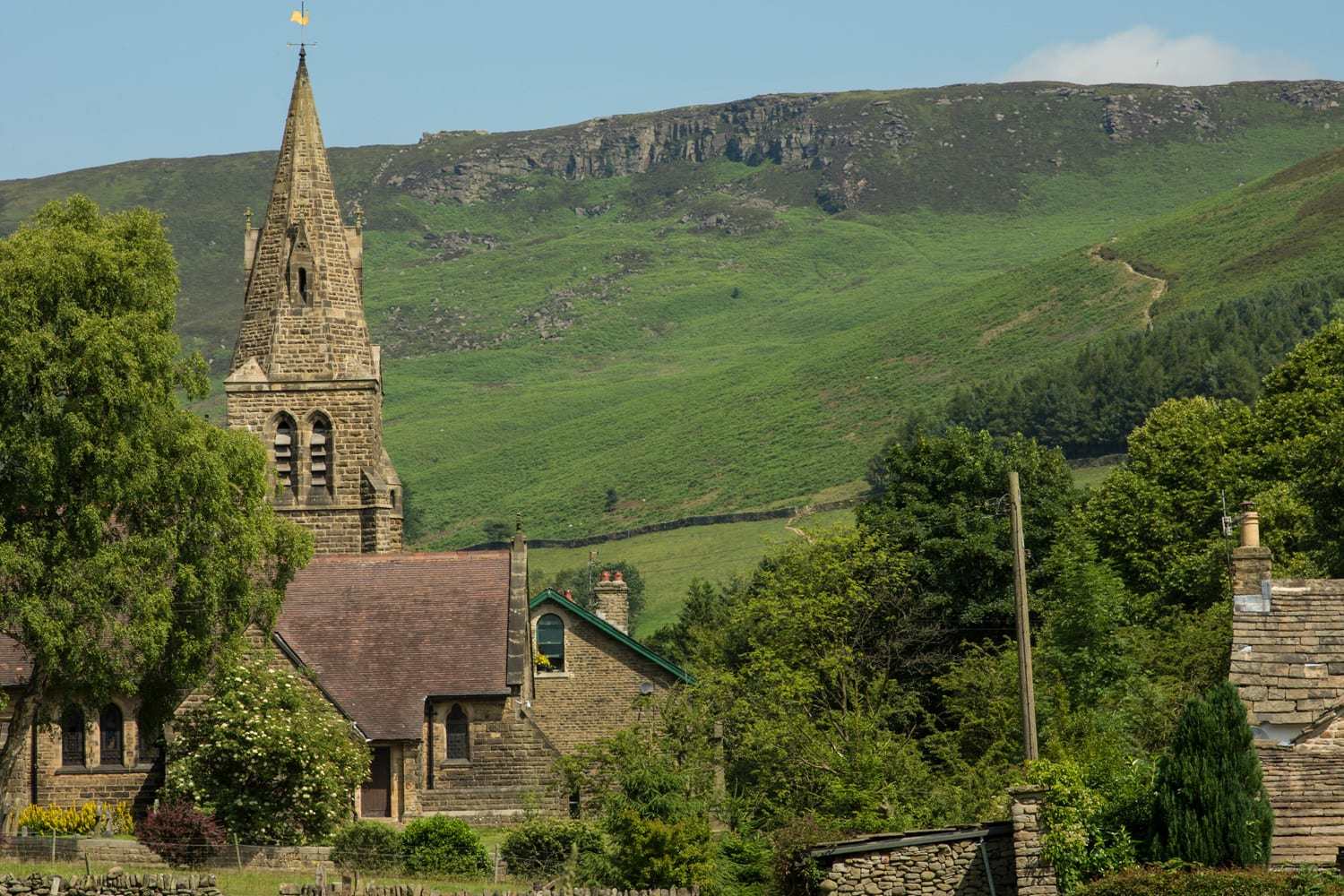 Village with a church spire in front of a hill